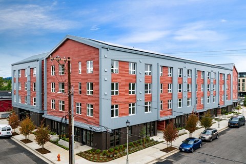 A red and grey building with a parking lot in front.