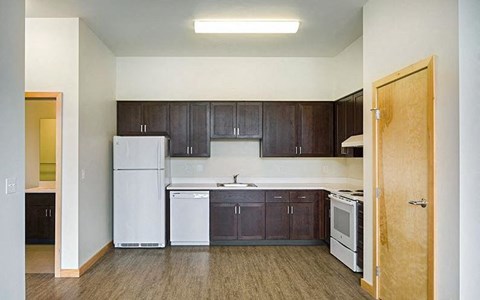 A kitchen with dark brown cabinets and white appliances.