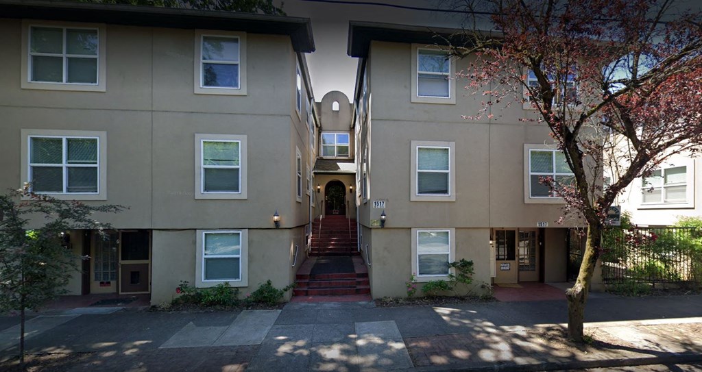 two buildings and a passage way between them with a tree in front on the right side