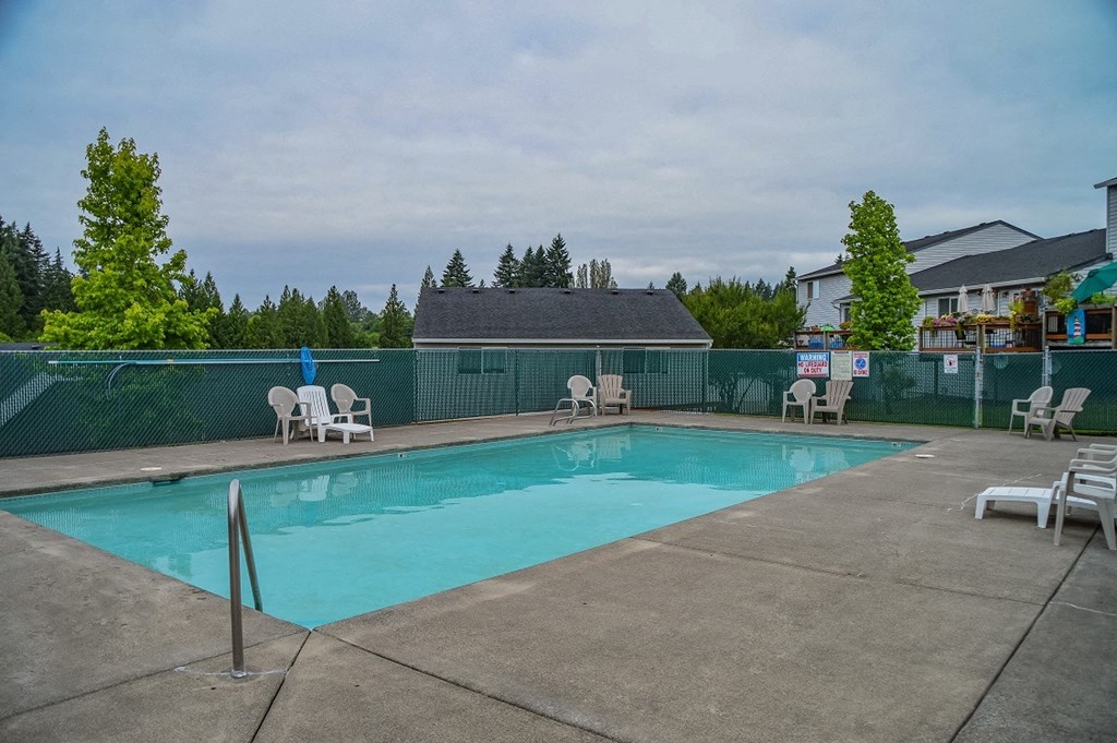 a swimming pool with chairs and a fence around it