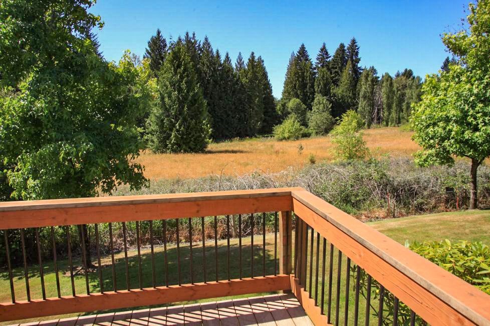 a deck with a view of a field and trees