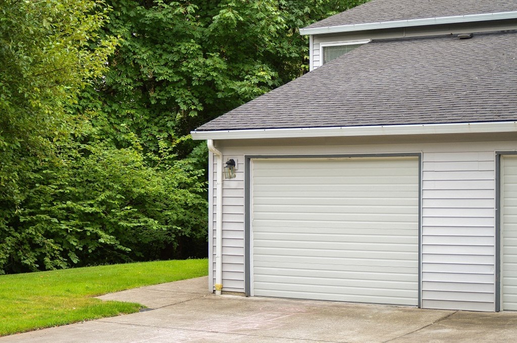 a white garage with a garage door on the side of a house
