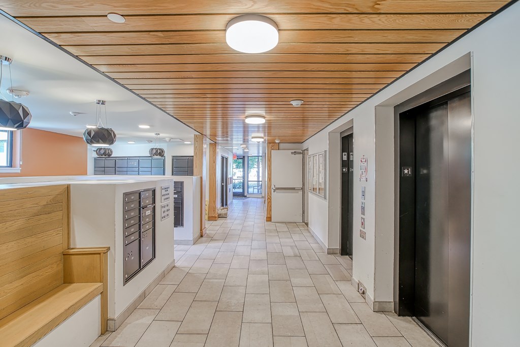 A long hallway with a wooden ceiling and tile flooring.