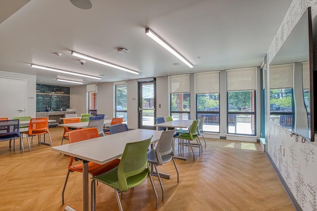 A room with tables and chairs and a white wall with black drawings on it.