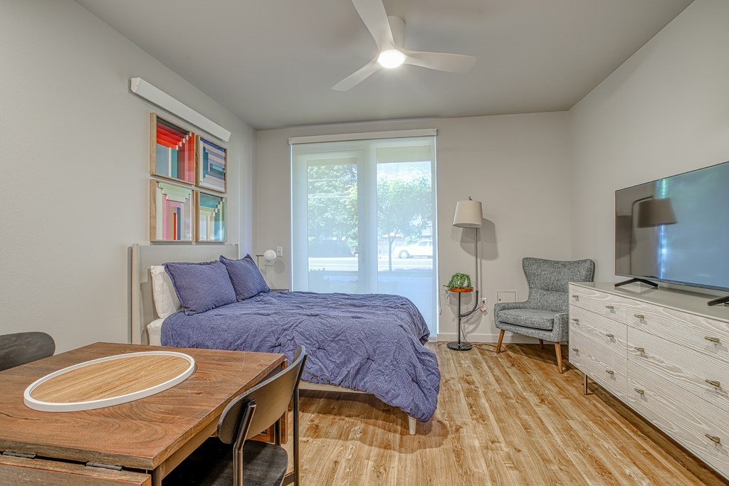 A bedroom with a bed, a chair, a dresser, and a ceiling fan.