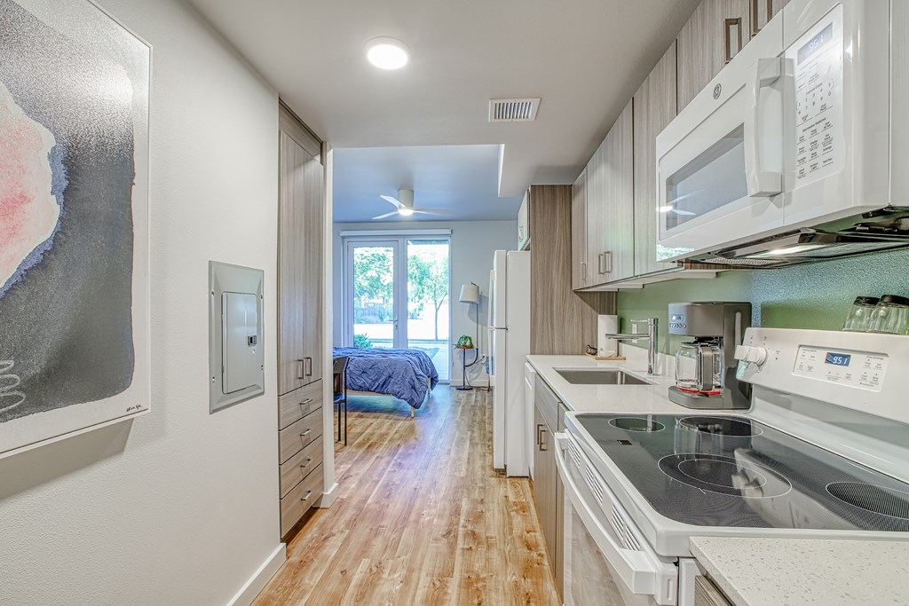 A kitchen with white appliances and wooden floors.