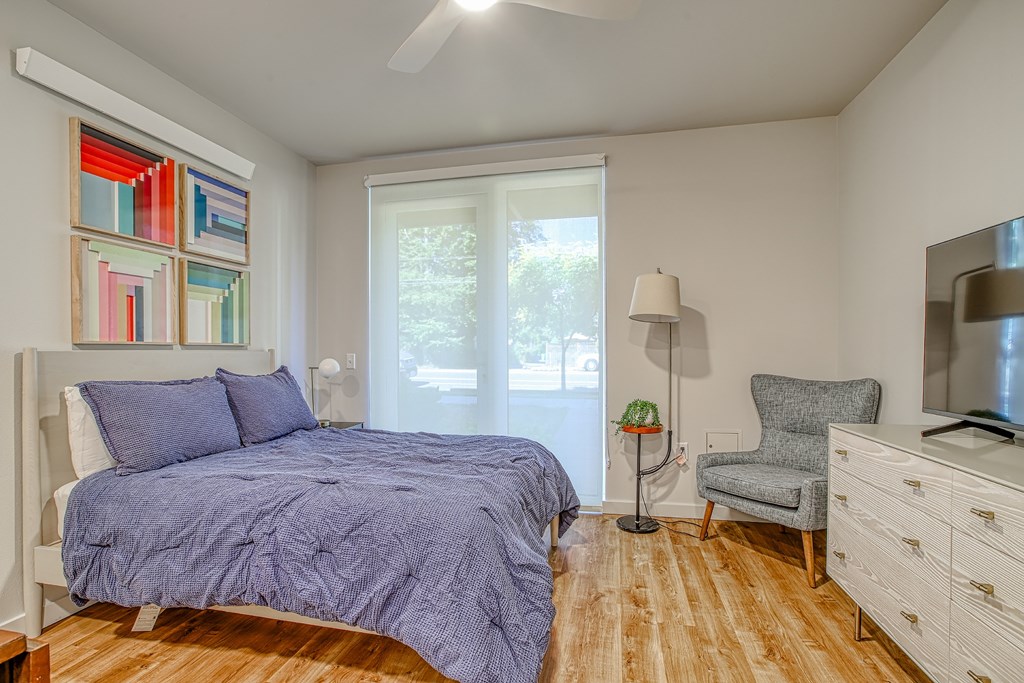 A bedroom with a bed, chair, and a painting on the wall.