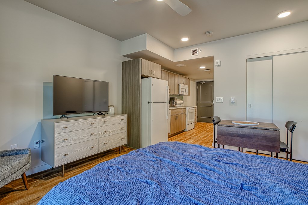 A bedroom with a blue bedspread and a television on a cabinet.