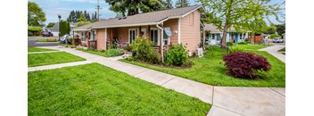 a small pink house with a sidewalk in front of it