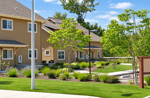 A row of houses with a green lawn in front.