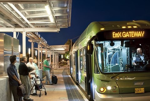 A bus is stopped at the Emx Gateway station with people waiting to board.
