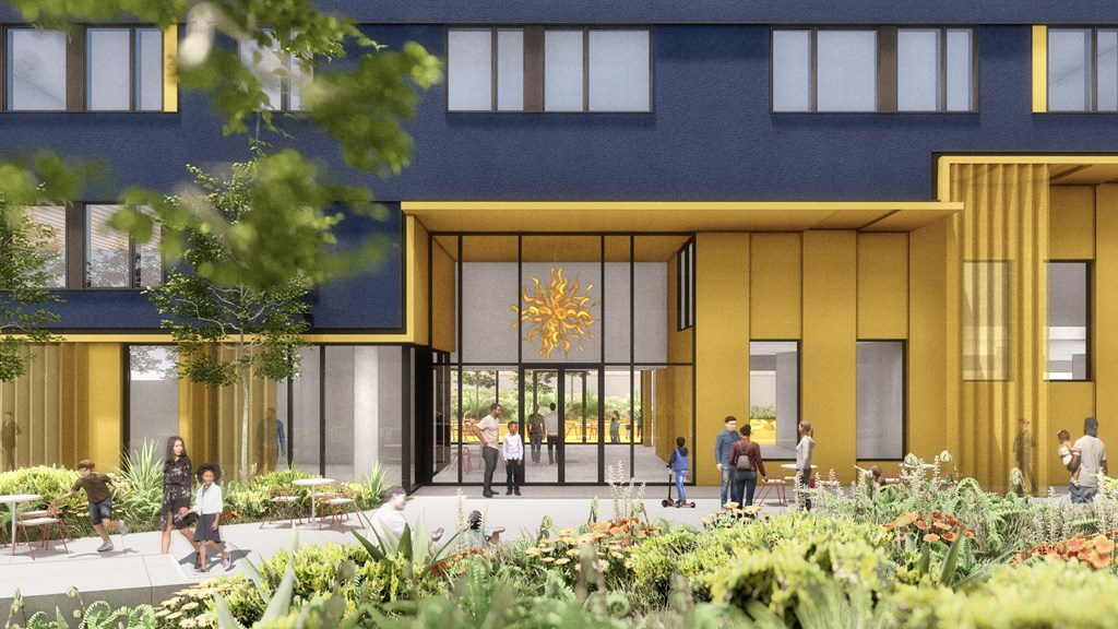 A modern building with a yellow entrance and people walking around.