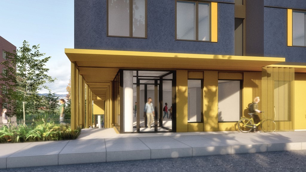 A modern building with a yellow entrance and people walking in.