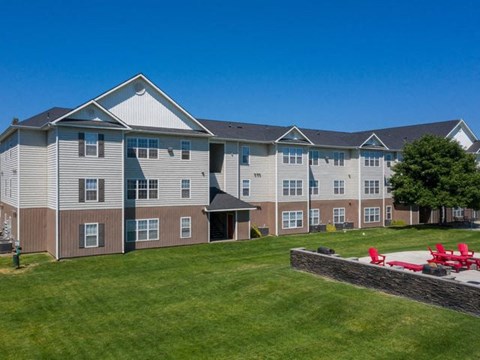 an apartment building with a yard and a fire pit