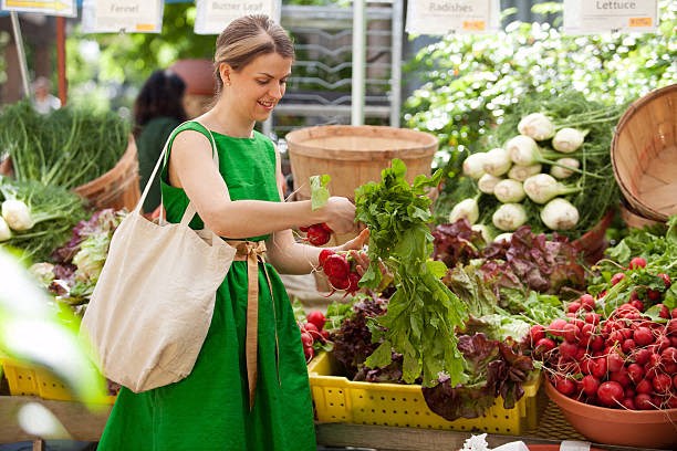 a woman is buying vegetables at a farmers market
