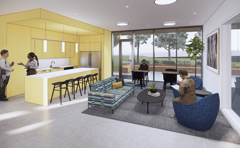 A modern kitchen with a yellow wall and people standing and sitting around it.