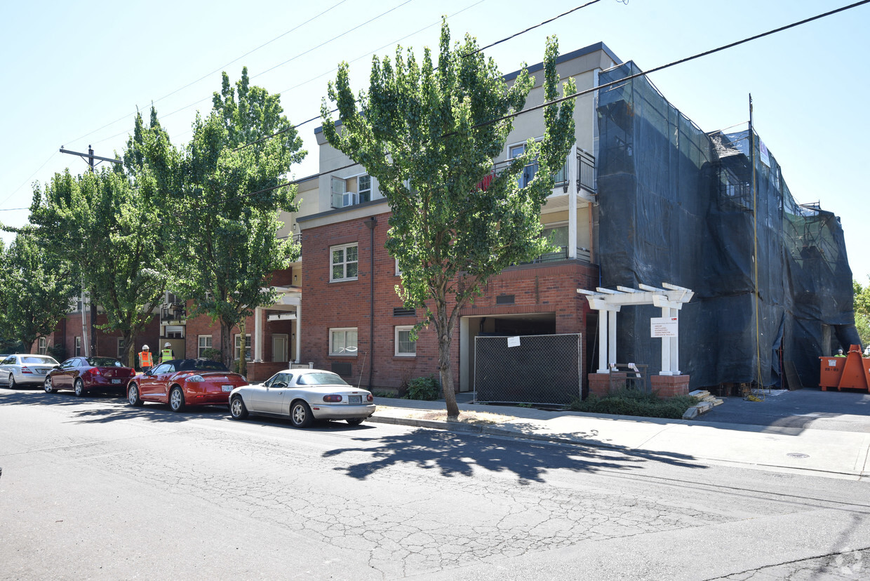 A red car is parked in front of a brick building.