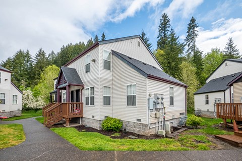 a white house with a porch and a deck on a street