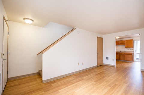 a living room with a white wall and wood floors