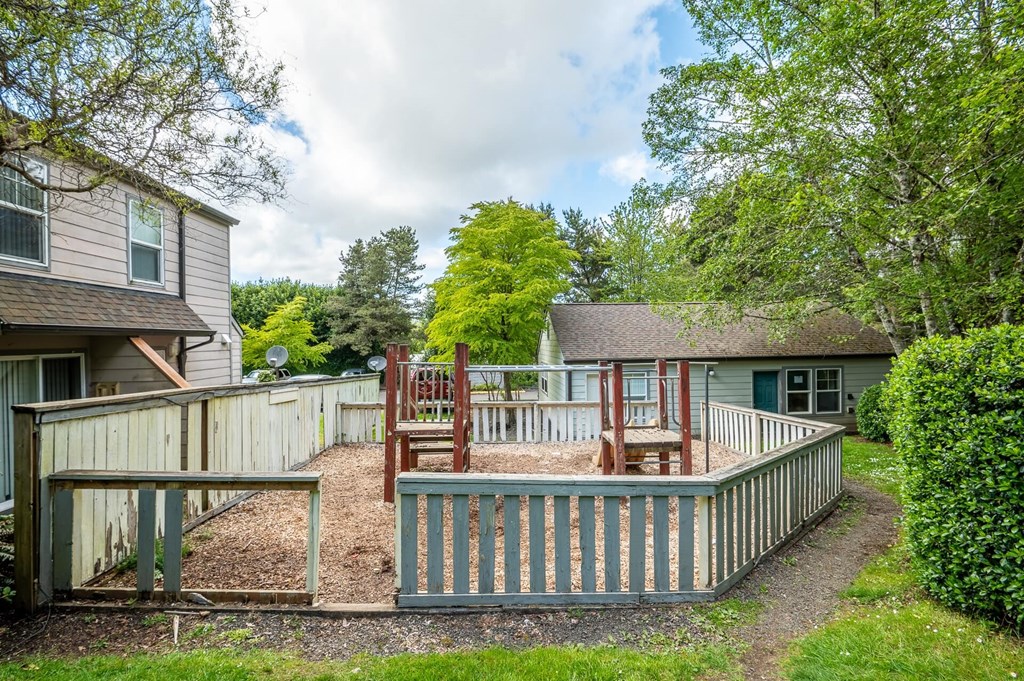 a backyard with a deck and a play yard with chairs