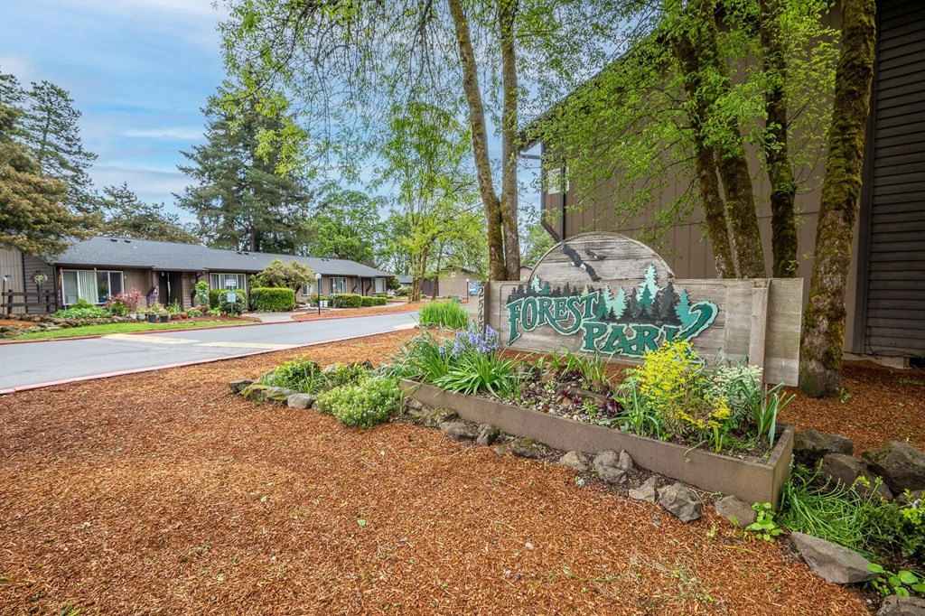 a community sign in front of a building with trees and a road