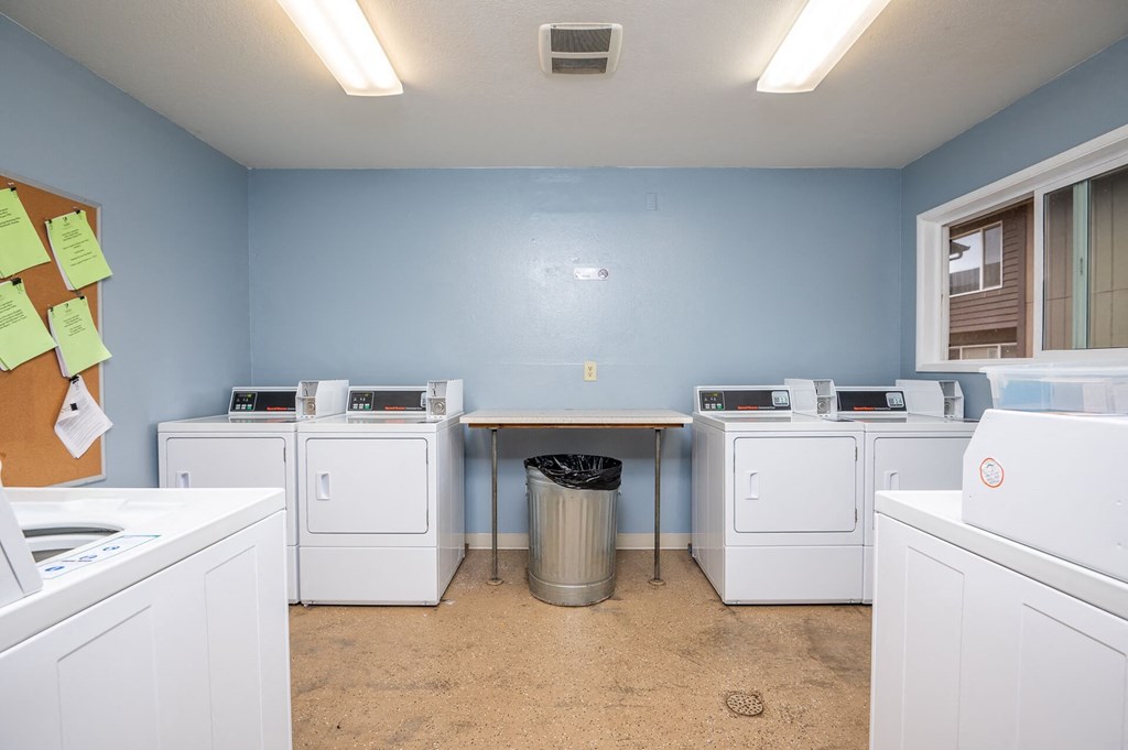 a washer and dryer room with laundry machines and a table