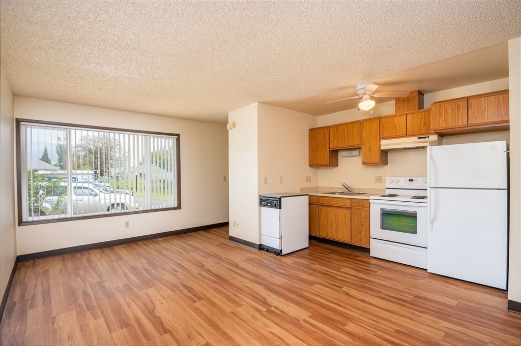 an empty kitchen with white appliances and wood floors