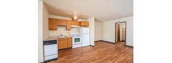 a kitchen with white appliances and wood flooring and a ceiling fan