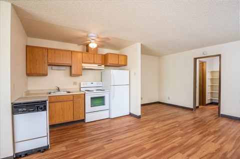 a kitchen with white appliances and wood flooring and a ceiling fan