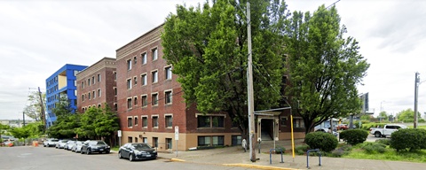 A red brick building with a parking lot in front.