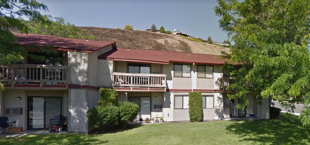 an apartment building with a hill in the background