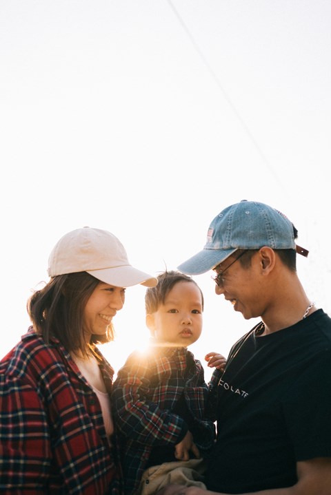 A family of three wearing hats and casual clothing are standing together.