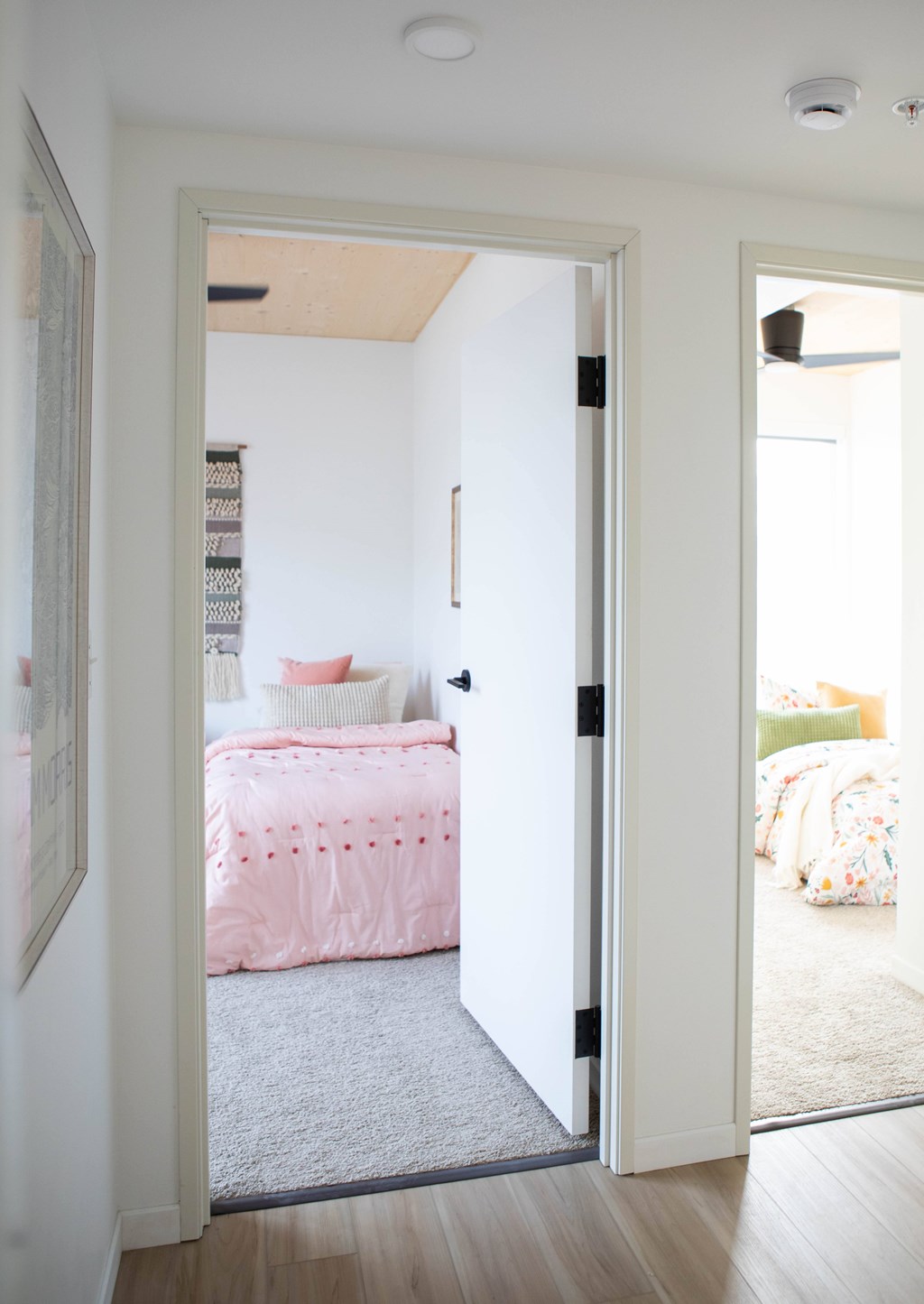 A white door opens to a room with a pink bed.