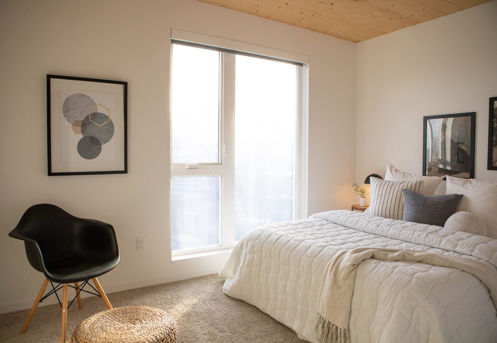 A bedroom with a large bed and a chair.