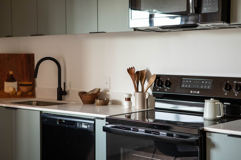 A modern kitchen with a black oven and a black faucet.