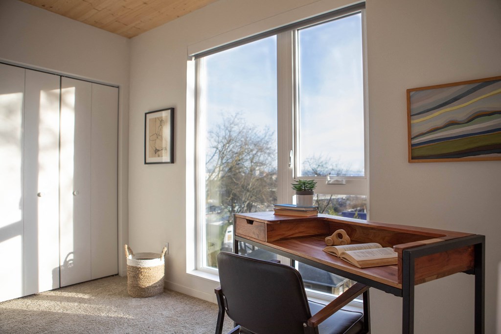 A room with a desk and chair in front of a large window.