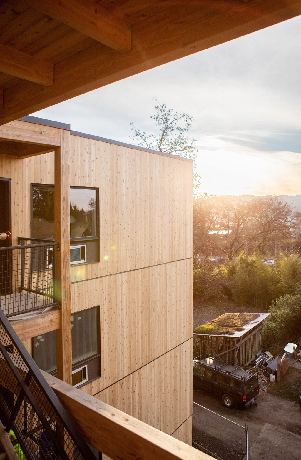 A modern wooden building with a balcony and a car parked outside.