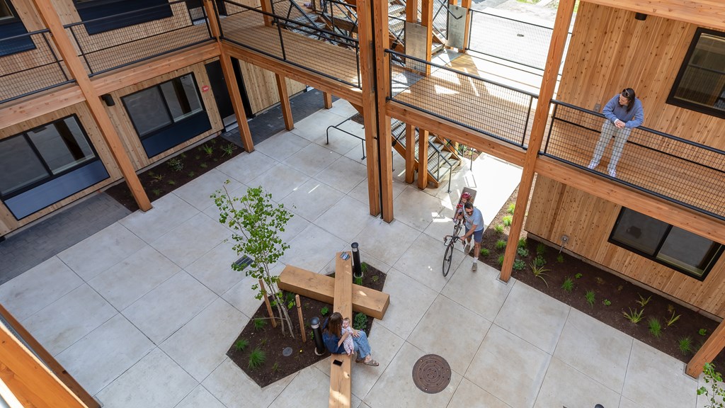 A man and a woman are sitting on a bench in a courtyard surrounded by wooden buildings.