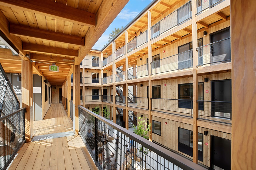 A wooden balcony with a railing and a green plant.