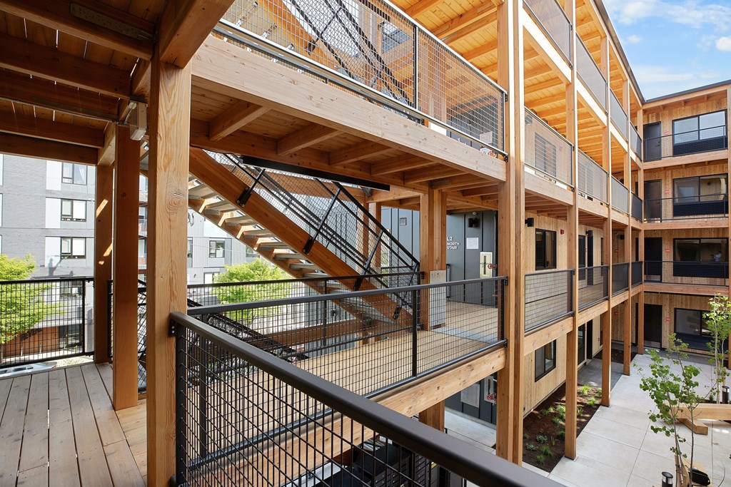 A wooden staircase with a metal railing connects the floors of a modern building.