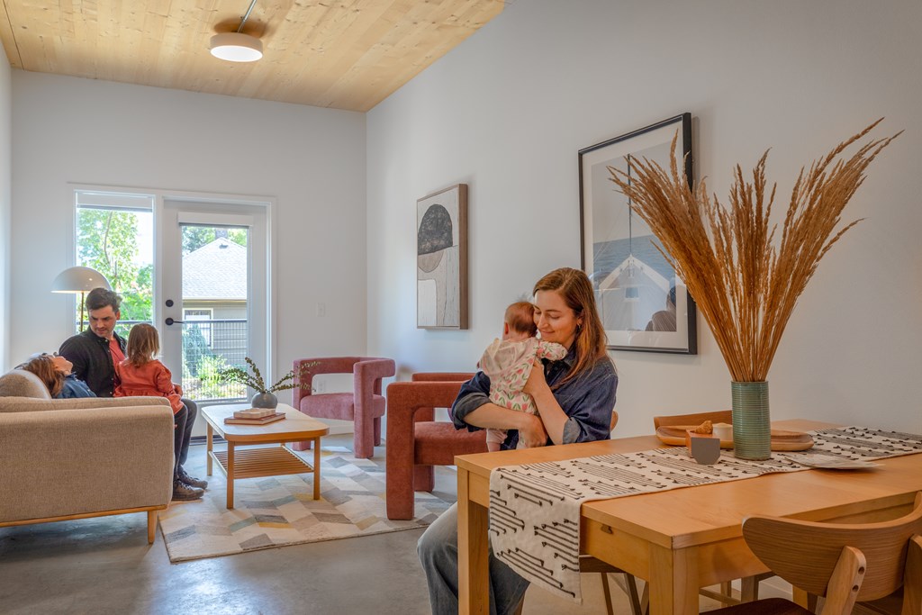 A family of three is sitting on a couch in a living room.