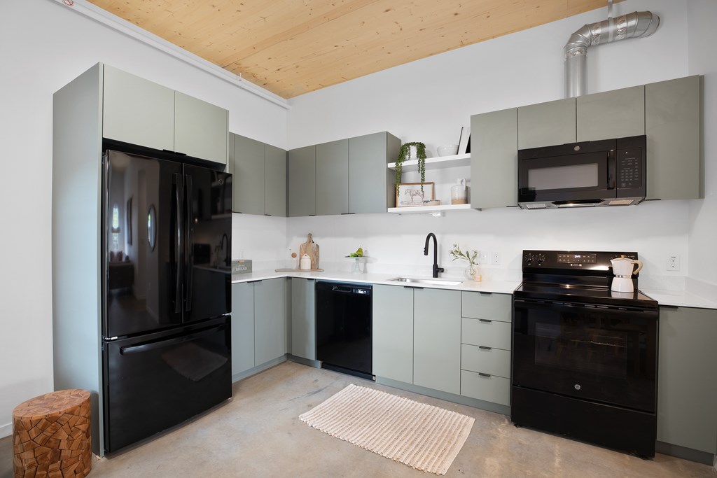 A kitchen with black appliances and grey cabinets.