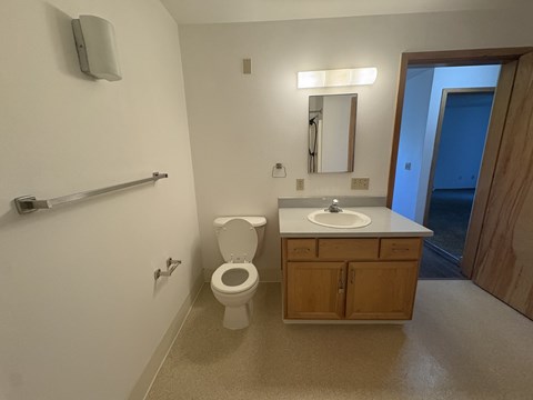 A bathroom with a toilet, sink, mirror, and a door.