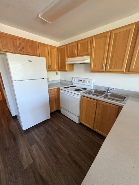 A white refrigerator stands in a kitchen with wooden cabinets.