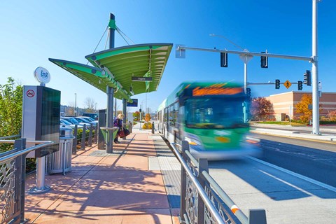 A bus is driving down the street past a bus stop.