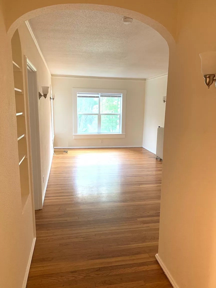 an empty room with wooden floors and a window