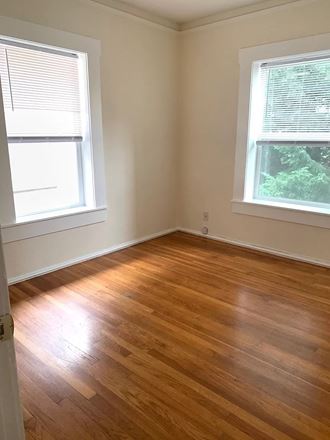 an empty room with a wooden floor and two windows