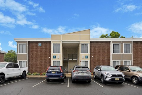 A parking lot in front of a building with cars parked.