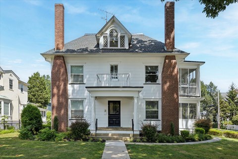A white house with a black roof and a chimney.