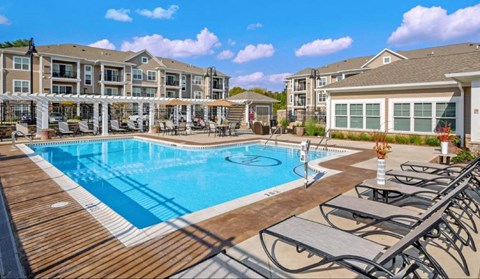 a swimming pool with patio furniture and apartments in the background